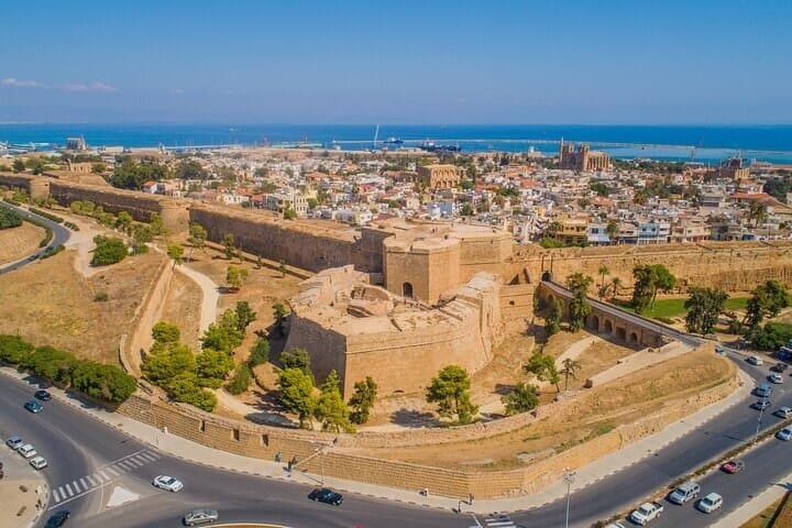 Massive ancient stone fortress and city walls in a coastal town by the blue sea.